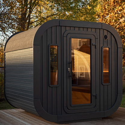 Outdoor sauna made of spruce wood with curved edges and tinted glass windows, designed for 4-6 persons. The sauna is black in color and appears to be situated in a backyard setting.